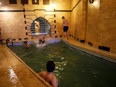Pengunjung pria berenang di kolam yang ada di pemandian umum Bab al-Ahmar Aleppo pada 11 April 2019.  Warga Suriah menghidupkan kembali tradisi mingguan mereka mengunjungi pemandian umum setelah perang selama bertahun-tahun yang melanda negara tersebut. (REUTERS/Omar Sanadiki)
