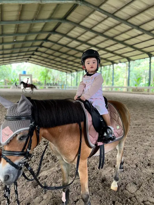 Guzel mengikuti jejak sang ibu yang menekuni berkuda. Duduk di atas kuda, Guzel kenakan overall pink dengan long sleeve cokelat [@guzelimalisyakieb]
