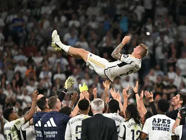 Gelandang Real Madrid #08 Toni Kroos terlempar ke udara oleh rekan satu timnya saat melawan Real Betis pada pekan ke-38 (pekan terakhir) La Liga 2023/2024 di Santiago Bernabeu, Minggu (26/5/2024). (JAVIER SORIANO / AFP)