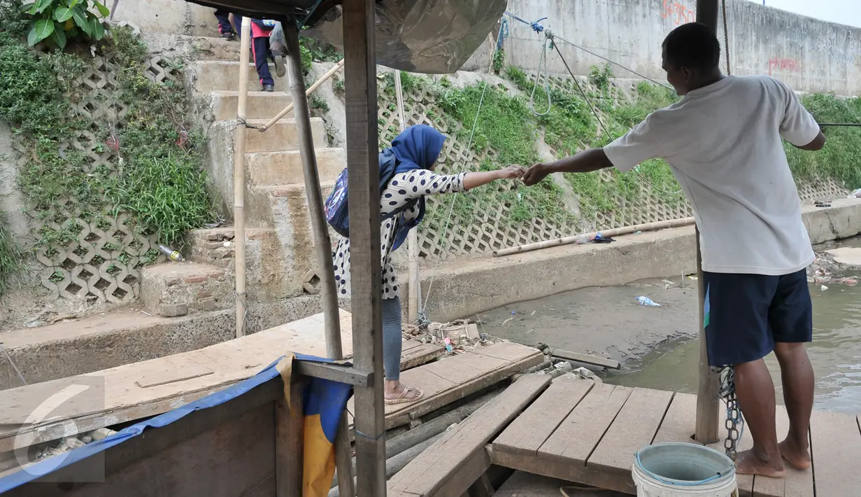 Mami mengambil uang hasil pembayaran warga yang menyeberang menggunakan perahu eretan, Jakarta, Rabu (28/12). Meski penumpang tak seramai dulu, perahu eretan tetap bertahan diantara tembok beton normalisasi kali Ciliwung. (Liputan6.com/Yoppy Renato)
