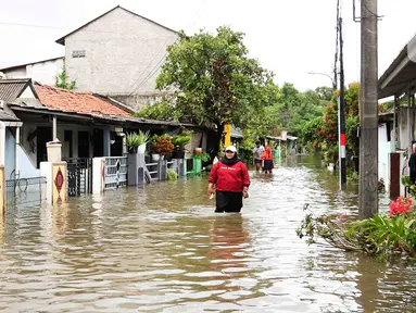 Warga melintasi genangan air di salah satu permukiman di kawasan Cakung, Jakarta Timur, Rabu (29/1/2025). (Liputan6.com/Herman Zakharia)