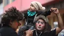 Seorang badut menggendong anaknya di atas bahu saat berpartisipasi dalam acara Hari Badut Nasional di ibu kota Peru, Lima, Kamis(25/5). Tanggal 25 Mei merupakan peringatan Hari Badut Nasional bagi warga Peru. (AP Photo/Martin Mejia)