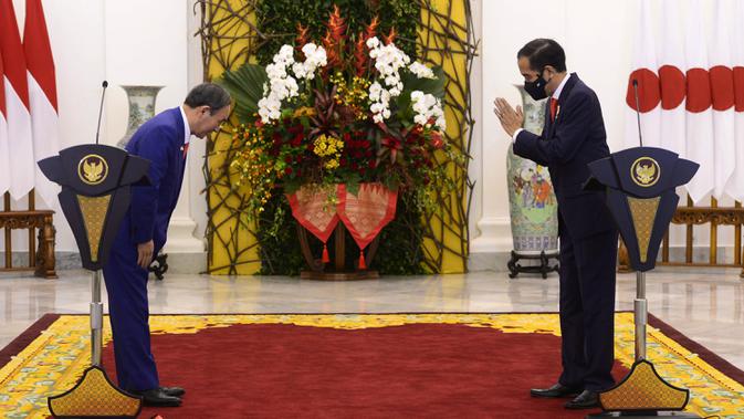 Perdana Menteri Jepang Yoshihide Suga (kiri) dan Presiden Joko Widodo (Jokowi) saling menyapa saat konferensi pers bersama di Istana Bogor, Selasa (20/10/2020). Lawatan kenegaraan tersebut dalam rangka meningkatkan hubungan bilateral antar kedua negara. (INDONESIAN PRESIDENTIAL PALACE / AFP)