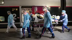Petugas medis membawa pasien virus corona COVID-19 di Stasiun Gare d'Austerlitz di Paris, Prancis, Rabu (1/4/2020). Prancis mengerahkan kereta kecepatan tinggi untuk mengevakuasi pasien COVID-19 dari Paris ke wilayah Brittany. (Thomas SAMSON/AFP/POOL)