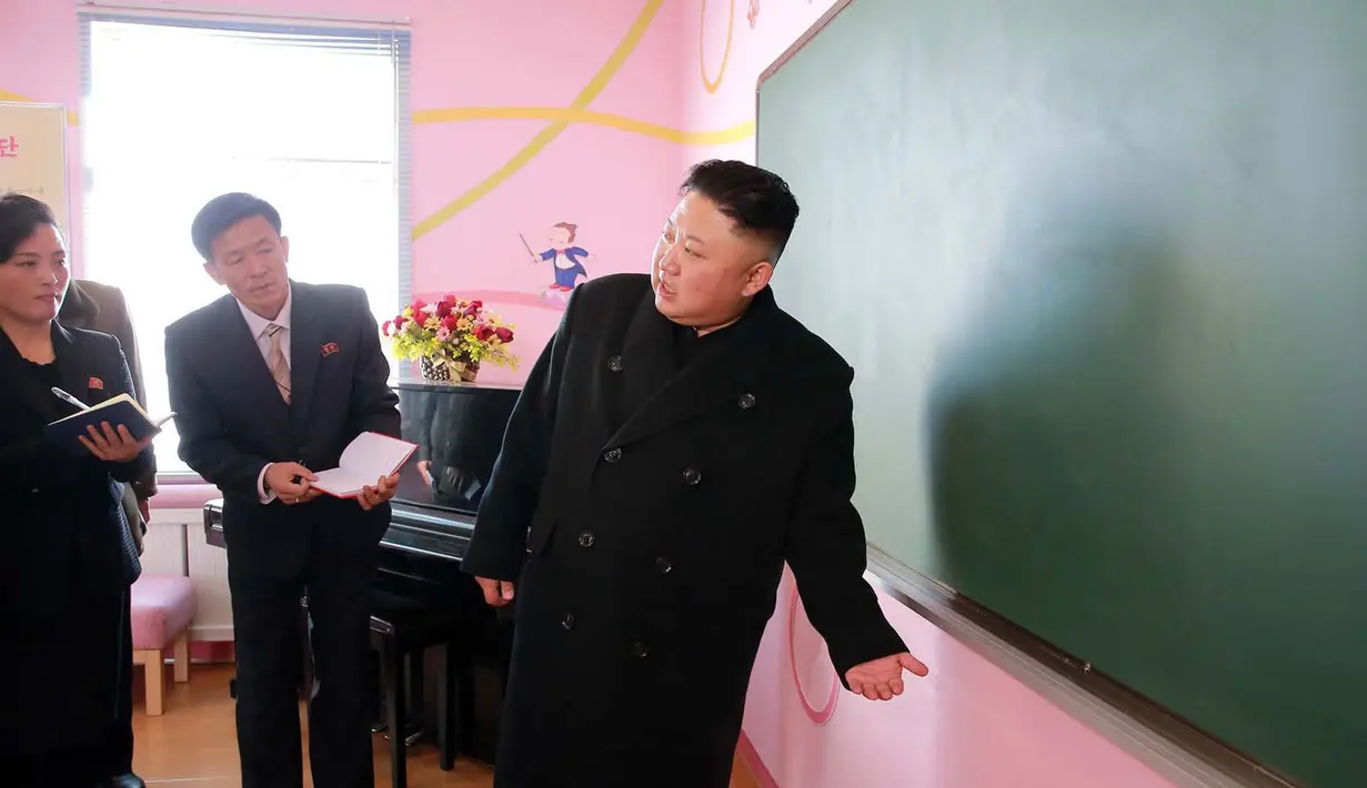 Kim Jong Un berbincang dengan para staf sekolah saat mengunjungi Sekolah Dasar Anak Yatim di Pyongyang (2/2). (AFP Photo / KCNA VIA KNS / STR)