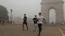 Sejumlah peserta yang mengikuti lomba New Delhi 10K berlari di depan India Gate yang diselimuti kabut tebal di New Delhi, India (31/10). Kabut asap ini diklaim sebagai kabut asap terparah yang dialami oleh New Delhi dalam 17 tahun. (AFP/Dominique Faget)