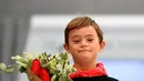 Anak laki-laki dengan down syndrome membawa buket bunga saat ambil bagian di atas catwalk pekan mode Petite Fashion Week di Madrid, 6 Oktober 2017. Tampil dalam balutan busana, mereka tampak menikmati tugasnya sebagai model. (GABRIEL BOUYS/AFP)