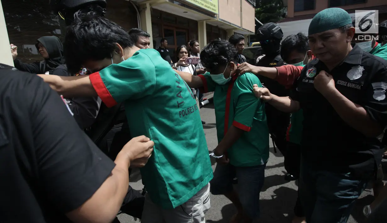 Petugas mengawal tersangka saat menggelar rilis pengungkapan 1,3 ton ganja di Polres Jakarta Barat, Kamis (4/1). Polres Metro Jakarta Barat berhasil menggagalkan penyelundupan 1,3 ton ganja dari Provinsi Aceh ke Jakarta. (Liputan6.com/Arya Manggala)