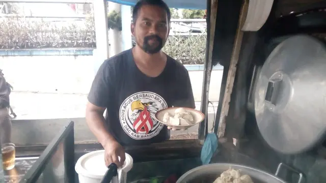 Agus Ilen, generasi kedua siomay legendaris mang Ilen Garut, tengah melayani pembeli yang antri membeli di lapak jualannya jalan Cimanuk Garut, Jawa Barat