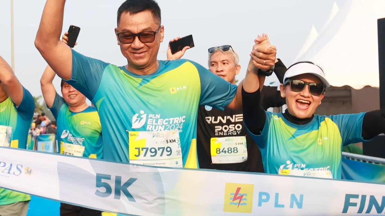 Direktur Utama PLN, Darmawan Prasodjo (kiri) bersama istri, Diny Darmawan Prasodjo (kanan) saat melintasi garis finish dan menyelesaikan PLN Electric Run 2024 kategori 5K