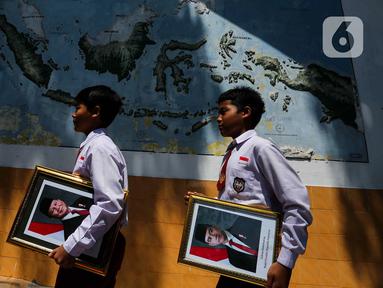 Dua murid Sekolah Dasar Negeri (SDN) Pondok Labu 14 membawa pigura foto Presiden Prabowo Subianto dan Wakil Presiden Gibran Rakabuming Raka, Jakarta, Selasa (22/10/2024). (Liputan6.com/Herman Zakharia)