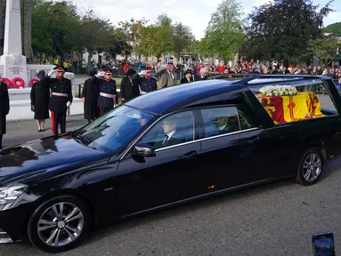 Warga berbaris saat mobil yang membawa peti berisi jenazah Ratu Elizabeth II melintas di Ballater, Skotlandia, Minggu (11/9/2022). Jenazah Ratu Elizabeth II diberangkatkan dari Kastil Balmoral ke Istana Holyroodhouse di Edinburgh sebelum nantinya akan dipindahkan ke London. (Andrew Milligan/PA via AP)