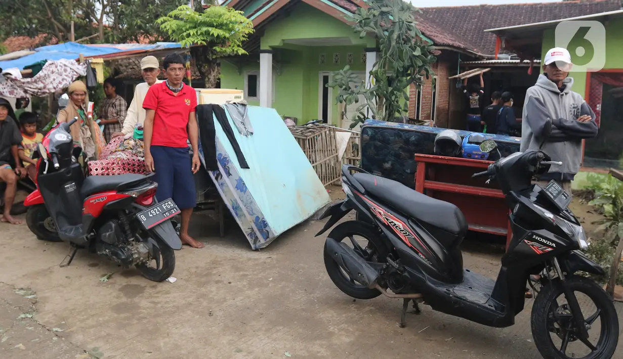 Keluarga Pak Supri berpose di depan kediamannya Desa Sumber Urip Pebayuran, Kabupaten Bekasi, Jawa Barat, Senin (22/2/2021). Banjir merenda keluarga tersebut merapikan barang-barang dan bersihkan rumah yang sudah surut. (Liputan6.com/Herman Zakharia)