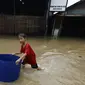Seorang anak berada di tengah banjir di jalan Merpati Raya kota,Tangerang Selatan, Selasa (21/2). Intensitas curah hujan yang tinggi di sertai buruknya Drainase menyebabkan banjir 50-100 cm di kawasan tersebut. (Liputan6.com/Helmi Afandi)