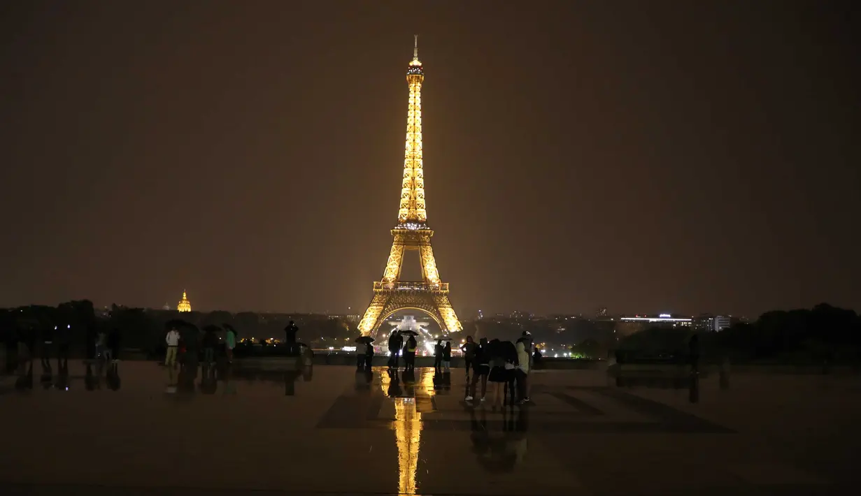 Sejumlah wisatawan menikmati pemandangan Menara Eiffel yang diterangi lampu dari Trocadero Plaza di Paris, Prancis (1/9).( AFP Photo/Ludovic Marin)