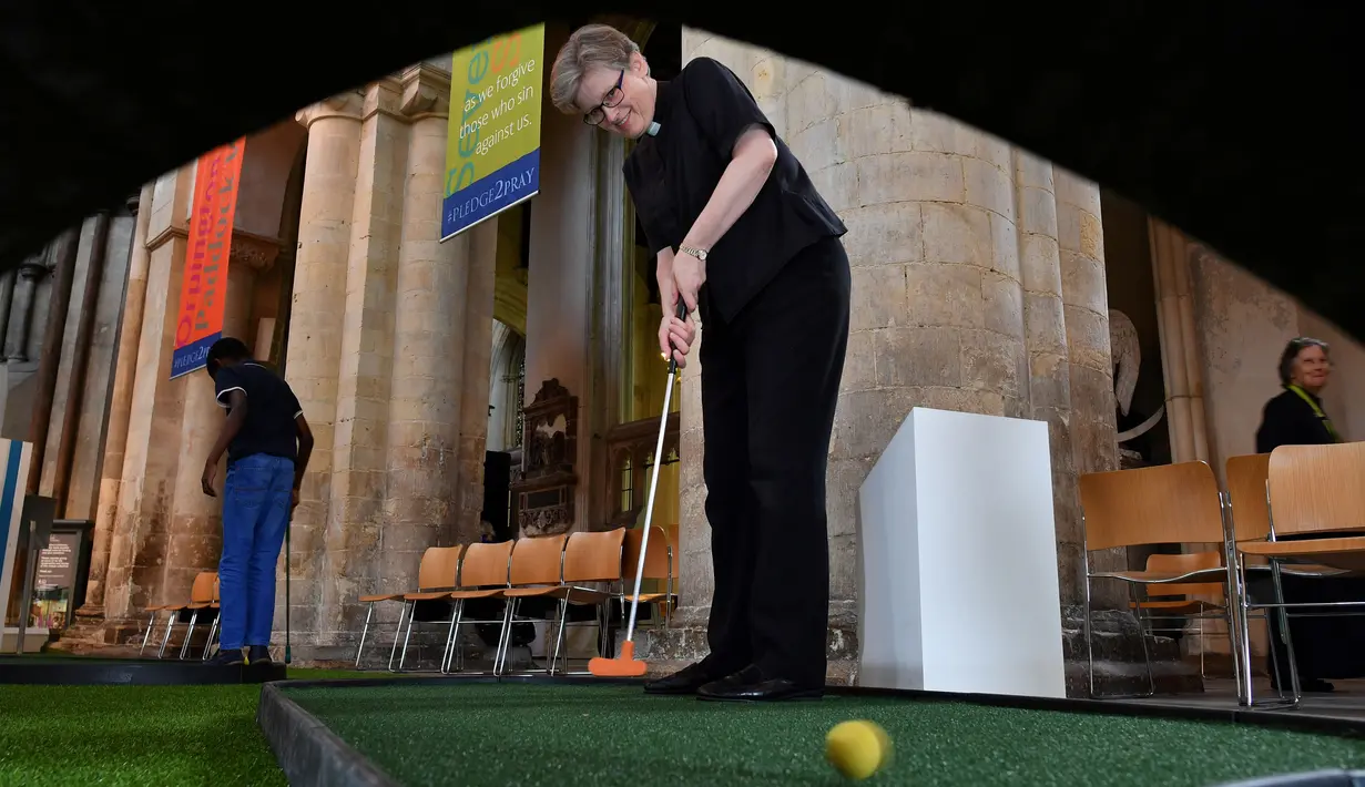 Pendeta Rachel Philips untuk Misi dan Pertumbuhan bermain di lapangan golf kecil yang didirikan di dalam Katedral Rochester, Inggris pada 6 Agustus 2019. Pengunjung dapat bermain secara gratis di lapangan golf yang berlangsung sepanjang Agustus ini. (Ben STANSALL / AFP)