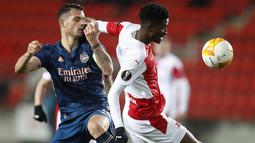 Penyerang Slavia Praha, Peter Olayinka berebut bola dengan gelandang Arsenal, Granit Xhaka pada leg kedua perempat final Liga Europa di Stadion Sinobo, Praha, Jumat (16/4) dini hari WIB.  Arsenal lolos ke semifinal Liga Europa setelah menang telak 4-0 di markas Slavia Praha. (AP Photo/Petr David Jo
