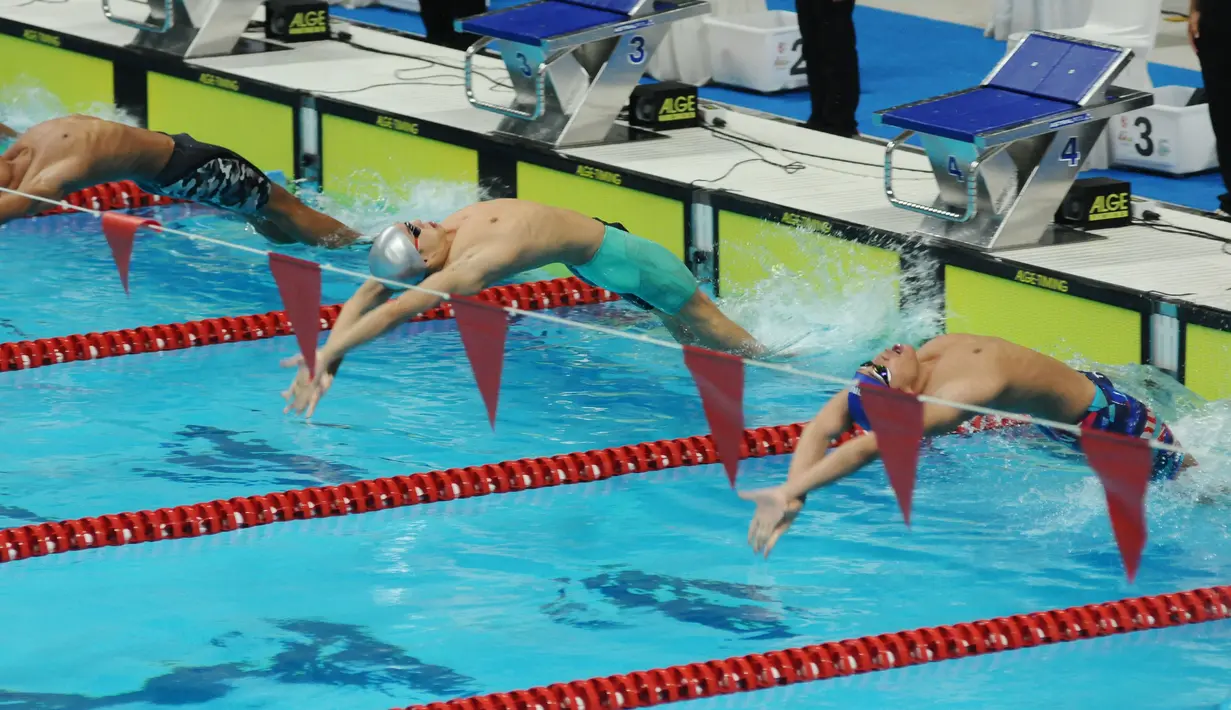 Perenang ESC Bandung, Ricky Anggawijaya (tengah) saat start di lomba 200 meter gaya punggung putra Kejuaraan Aquatik Indonesia Open 2017 di Stadion Aquatik GBK, Jakarta, Jumat (15/12). Ricky mencatat waktu 02.04,75 detik. (Liputan6.com/Helmi Fithriansyah)