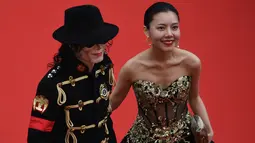 Seorang pria berpenampilan Michael Jackson didampingi wanita cantik menghadiri pemutaran film Solo: A Star Wars Story di Festival Film Cannes, Prancis, Selasa (15/5). Belum diketahui dengan pasti siapa pria tersebut. (AFP/Antonin THUILLIER)