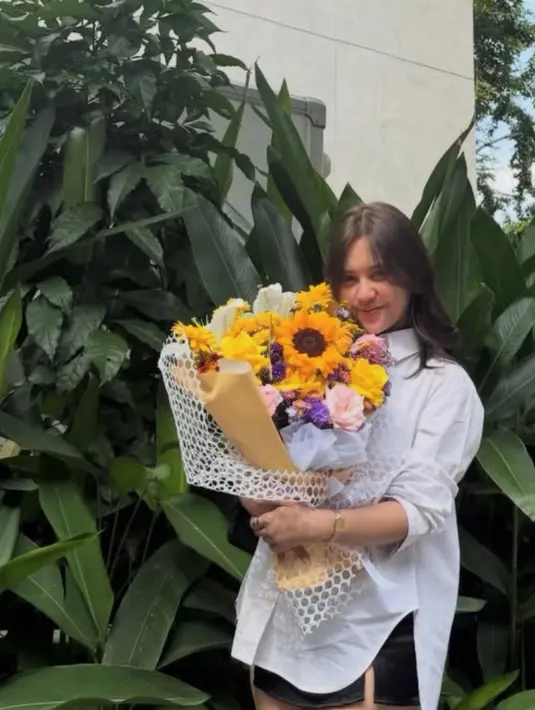 Ziva Magnolya terlihat memegang buket bunga bernuansa kuning. Ia pun tampil dengan kemeja putih lengan panjang oversize dipadukan mini skirt. [@zivamagnolya]