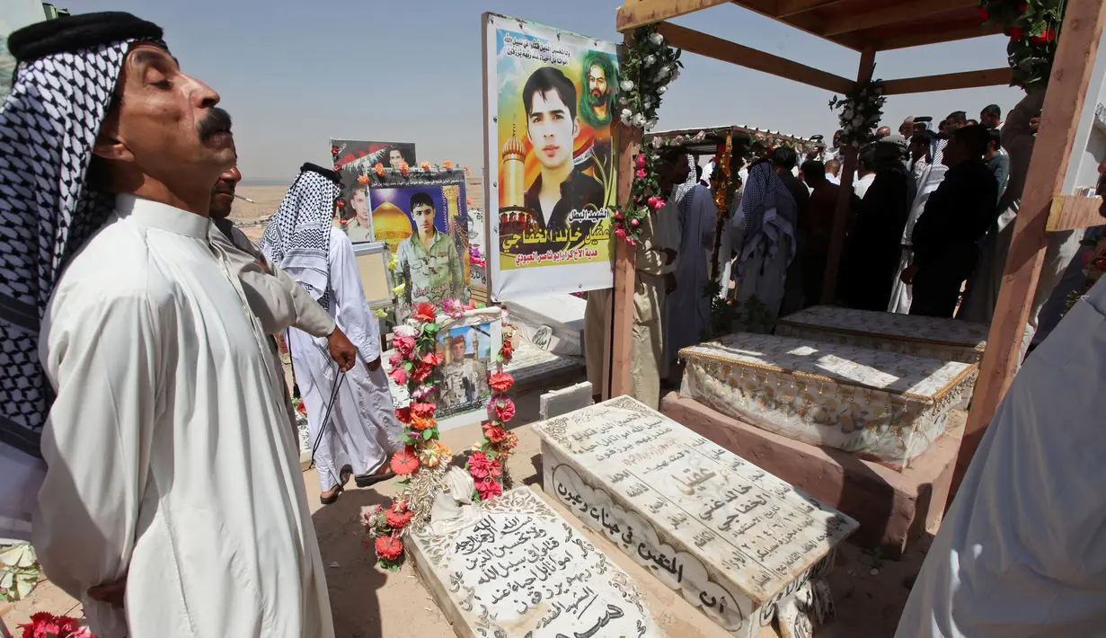 Warga mengunjungi makam kerabat mereka di pemakaman Wadi al-Salam, di Najaf, selatan Baghdad, Irak, 27 Juli 2016. Selama perang Irak tahun 2003, kompleks pemakaman ini sering digunakan sebagai tempat bersembunyi pejuang Irak. (REUTERS/Alaa Al-Marjani)