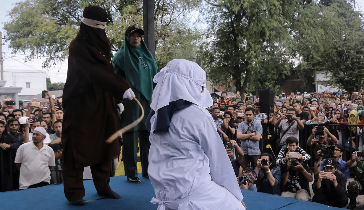 Petugas syariah mencambuk pekerja seks komersial (PSK) online di halaman Masjid Jamik Lueng Bata, Banda Aceh, Aceh, Jumat (20/4). Dua PSK online yang dicambuk berinisial MR (24) dan NA (22). (AP Photo/Heri Juanda)