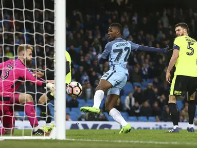 Pemain Manchester City, Kelechi Iheanacho (tengah) mengecoh kiper Huddersfield Town dengan golnya pada laga Piala FA putaran kelima di Etihad stadium, Manchester, Wednesday, (1/3/2017). Man.City menang 5-1. (AP/Dave Thompson)