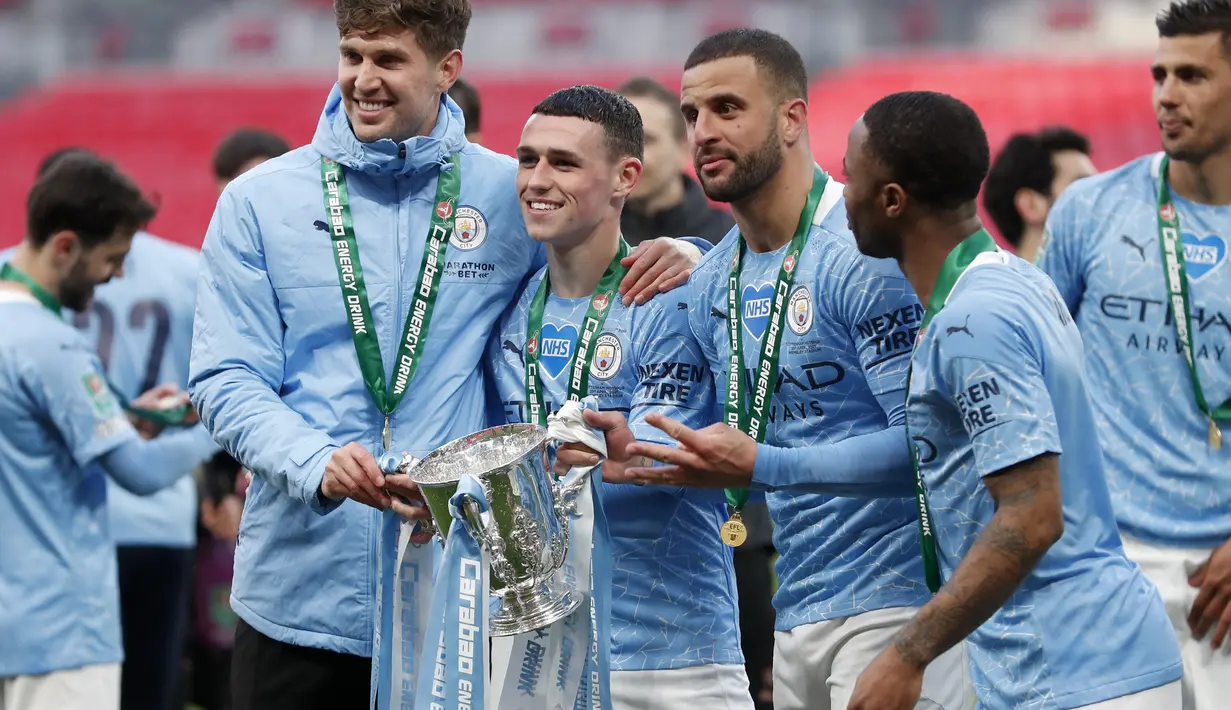 Pemain Manchester City John Stones, Phil Foden, Kyle Walker dan Raheem Sterling berpose dengan trofi saat merayakan kemenangan atas Tottenham Hotspur pada pertandingan final Piala Liga Inggris di stadion Wembley di London, Senin (26/4/2021). (AP Photo/Alastair Grant)