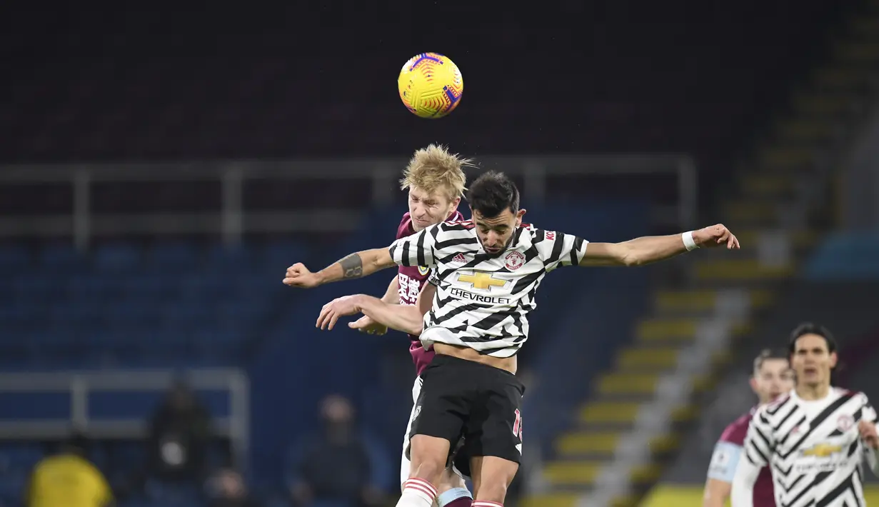Bek Burnley, Ben Mee berebut bola dengan gelandang Manchester United, Bruno Fernandes dalam partai tunda Liga Inggris 2020/21 di Turf Moor, Rabu (13/1/2021) dini hari WIB. Manchester United sukses mengalahkan Burnley dengan skor tipis 1-0. (Peter Powell/Pool via AP)