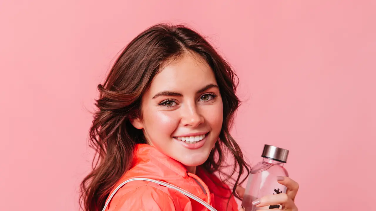 Seorang perempuan sedang menggenggam sebuah botol parfum (Foto Dok: Freepik/lookstudio)