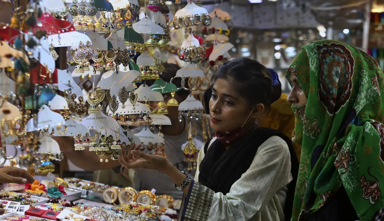 <p>Gadis-gadis muda melihat-lihat perhiasan buatan tradisional saat dia dan yang lainnya mengunjungi pasar untuk berbelanja perayaan Idul Fitri mendatang, di Karachi, Pakistan, Jumat, 29 April 2022. Idul Fitri menandai akhir bulan suci Ramadhan. (AP Photo/Fareed Khan)</p>