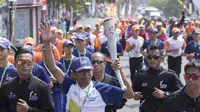Legenda balap sepeda Indonesia, Sutiyono, membawa obor pada pawai Asian Games di Bandar Lampung, Rabu (8/8/2018). (Bola.com/Reza Bachtiar)