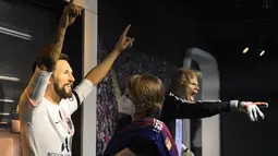 Seorang tim potret museum lilin Madame Tussauds Berlin, Karen Fries (kanan) memperbaiki jersey baru Paris Saint-Germain (PSG) pada patung lilin Lionel Messi di Berlin. (11/7/2021). (AFP/Tobias Schwarz)