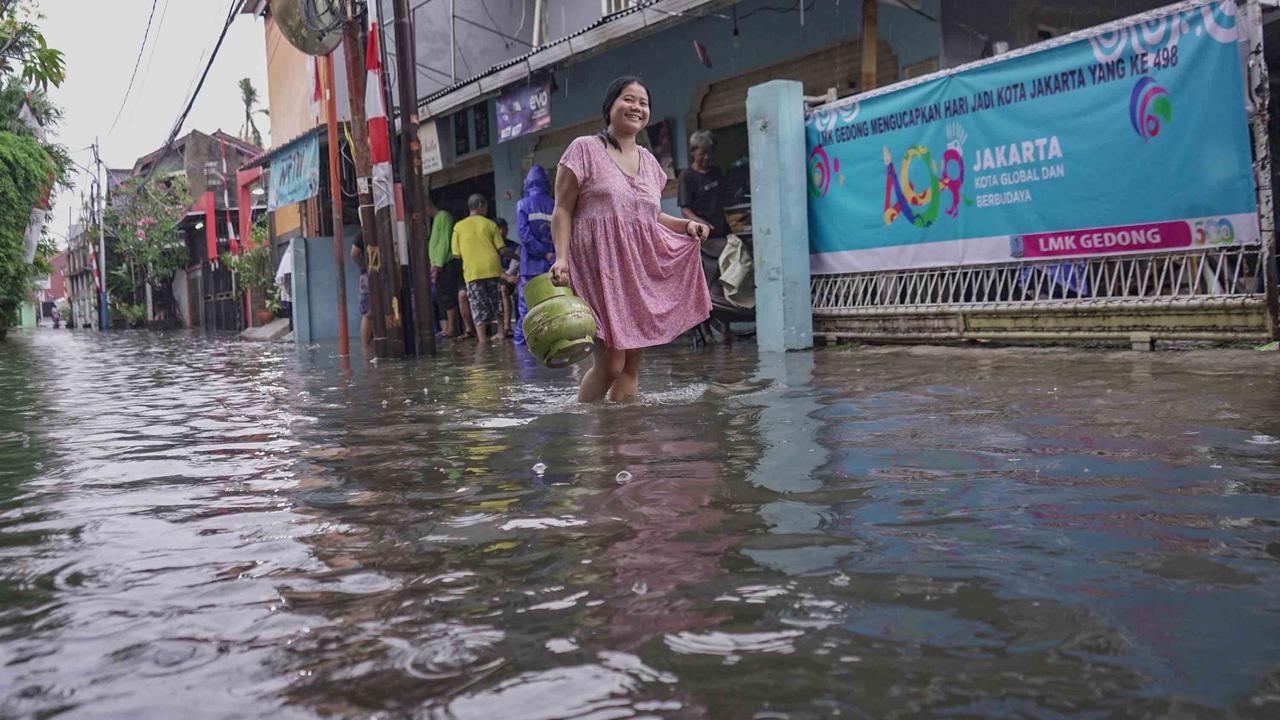 FOTO: Drainase Meluap, Warga Pasar Rebo Terobos Genangan