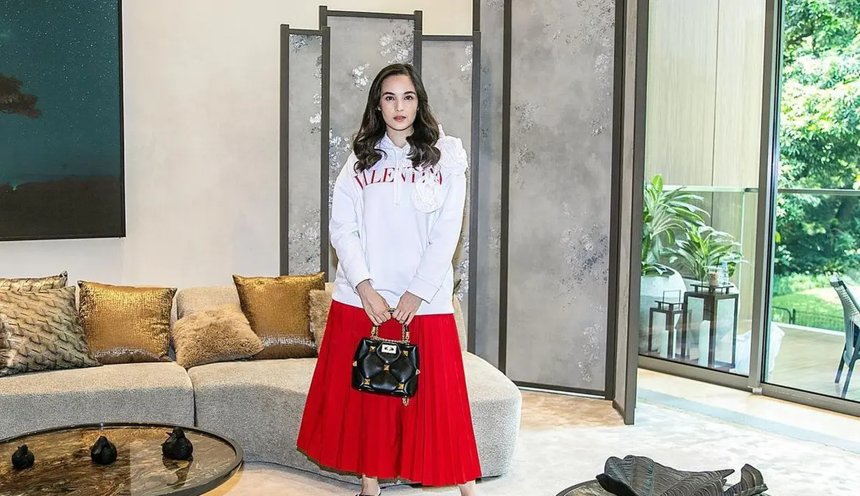 Ciptakan kesan elegan pada tampilan kasualmu dengan padu padan hoodie putih, rok plisket, pointed heels, dan mini bag seperti potret Chelsea Islan yang satu ini. (Instagram/chelseaislan).