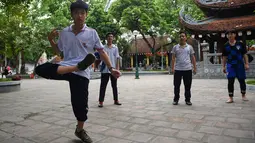 Pemuda Vietnam memainkan permainan "da cau" atau bulutangkis menggunakan bagian tubuh di dalam kompleks kuil Budha di Hanoi pada 25 Oktober 2019. Pemain berusaha menjaga agar kok tidak menyentuh tanah dengan menggunakan bagian tubuh selain tangan. (Nhac NGUYEN / AFP)