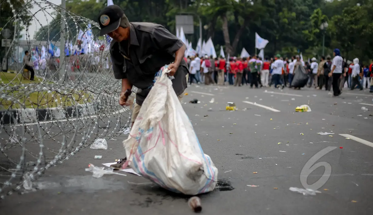 Pemulung memungut sampah saat peringatan hari buruh sedunia yang jatuh pada tanggal 1 Mei di depan Istana Merdeka, Jakarta, Jumat (1/5/2015). Aksi demo May Day menyisahkan sejumlah sampah berserakan di jalan. (Liputan6.com/Faizal Fanani)