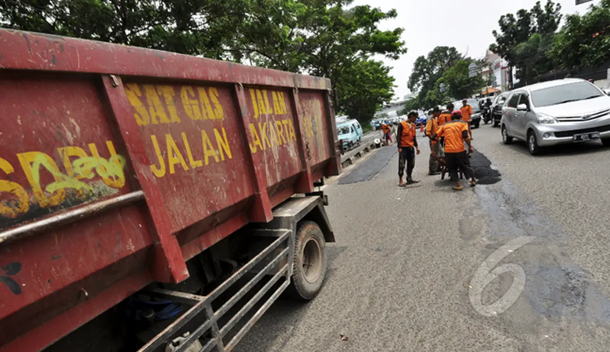 Sejumlah petugas mengaspal jalanan yang berlubang di Jalan Kramat Raya, Jakarta, Rabu (25/2/2015). Pascabanjir beberapa waktu lalu, sebanyak 700 titik lubang bermunculan di jalan Ibukota. (Liputan6.com/Faizal Fanani)