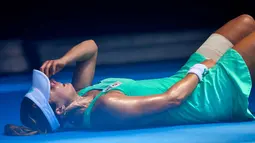 Petenis Prancis, Alize Cornet tergeletak di lapangan akibat cuaca yang begitu panas saat bertanding melawan petenis Belgia Elise Mertens di kejuaraan tenis Australia Terbuka di Melbourne, Australia, (19/1). (AP Photo / Andy Brownbill)