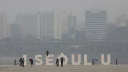 Seorang wanita mengenakan masker berpose saat pemandangan kota ditutupi dengan kabut tebal partikel debu halus di Seoul, Korea Selatan, Selasa (5/3). (AP Photo/Ahn Young-joon)