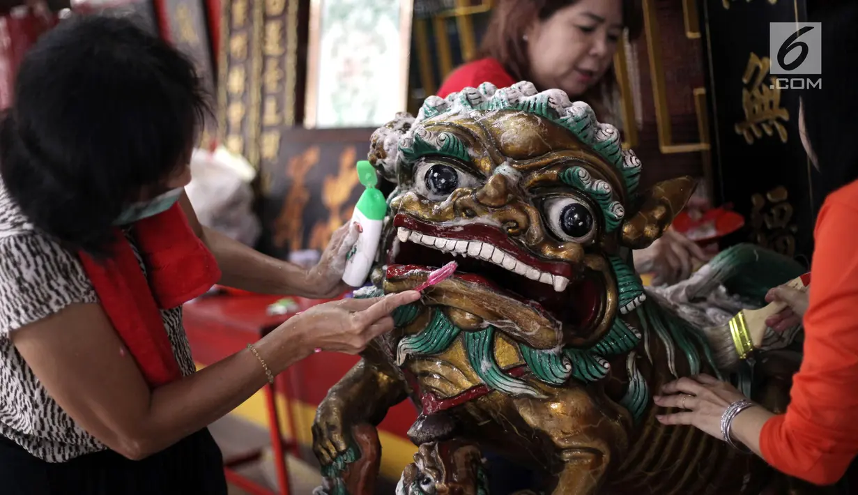 Seorang ibu menggosok patung menggunakan sikat saat aksi bersih-bersih di Vihara Amurva Bhumi, Jakarta, Kamis (8/2). Dengan suka cita,masyarakat Tionghoa membersihkan seluruh patung dewa-dewi serta perlengkapan ibadah. (Liputan6.com/Arya Manggala)