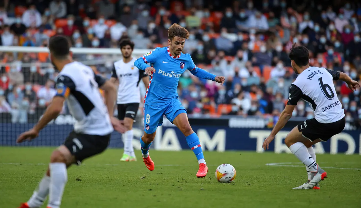 Penyerang Atletico Madrid, Antoine Griezmann (tengah) berlari membawa bola melawan Valencia pada pertandingan lanjutan La Liga Spanyol di stadion Mestalla di Valencia (8/11/2021). Valencia bermain imbang atas Atletico Madrid 3-3. (AFP/Jose Jordan)