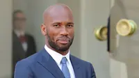 Didier Drogba saat tiba menghadiri undangan makan siang Presiden Liberia George Weah dan Presiden Prancis Emmanuel Macron di Istana Elysee di Paris, (21/2). Mantan penyerang Chelsea ini tampil dengan setelan jas berwarna biru. (AFP Photo/Ludovic Marin)