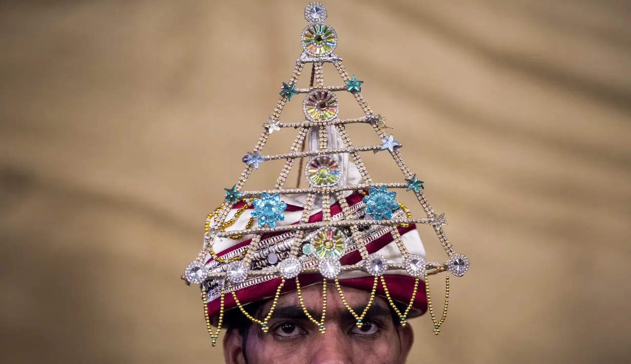 Pengantin pria mengenakan hiasan saat menjalani prosesi pernikahan massal di Karachi, Pakistan, (19/3). Sebanyak 62 pasangan pengantin mengikuti pernikahan massal yang merupakan bagian dari perayaan Festival Holi. (AFP Photo /Asif Hassan)
