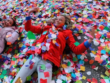 Dua orang remaja bermain confetti saat perayaan tahun baru di Times Square, New York, AS (1/1). Confetti adalah beragam potongan kertas, milar atau bahan logam yang biasanya dihamburkan dalam sebuah parade atau perayaan. (Reuters/Stephanie Keith)