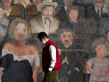 Seorang pria yang memakai masker berjalan melewati mural di bagian Hollywood Los Angeles, California, Amerika Serikat, Kamis (12/11/2020). California menjadi negara bagian kedua selain Texas yang mencatat 1 juta kasus infeksi virus corona COVID-19. (AP Photo/Jae C. Hong)