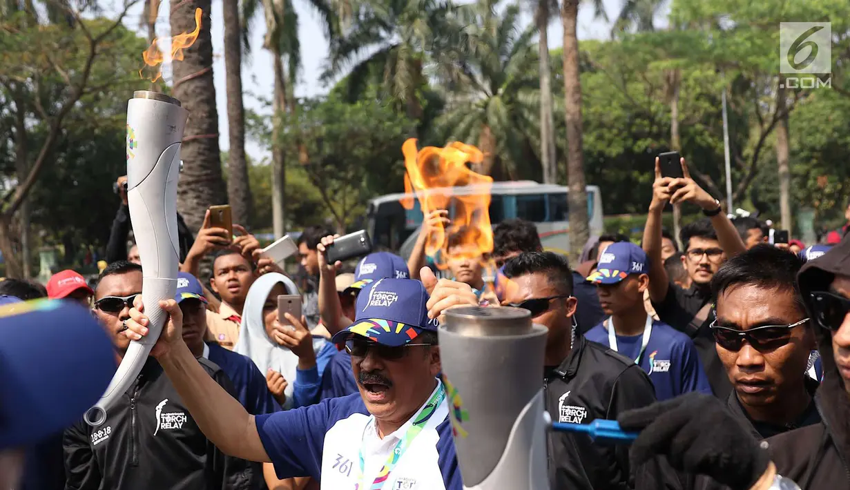 Pelari membawa obor Asian Games 2018 dalam Torch Relay Asian Games 2018 di kawasan TMII, Jakarta, Rabu (15/8). Pada Jumat (17/8), kirab obor berlanjut di wilayah Kab Administrasi Kepulauan Seribu, lalu ke Monas dan Istana. (Liputan6.com/Immanuel Antonius)