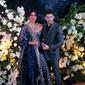 Pasangan aktris Bollywood Priyanka Chopra dan musisi Nick Jonas berpose untuk resepsi kedua pernikahan mereka di Mumbai, India, Rabu (19/12). Nick Jonas tampil klasik dan chic mengenakan setelan biru tua dan kemeja hitam. (AP/Rajanish Kakade)