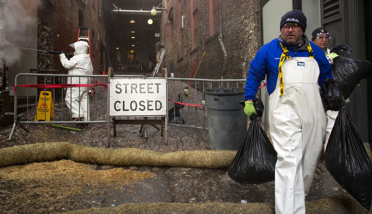 Petugas membawa kantong plastik yang berisi permen karet dari dinding  di Pike Place Market, Seattle, Rabu (11/11). Diperkirakan  satu juta permen karet melekat pada tembok yang dikenal "tembok permen karet" itu sejak tahun 1991. (AFP PHOTO/Jason Redmond)