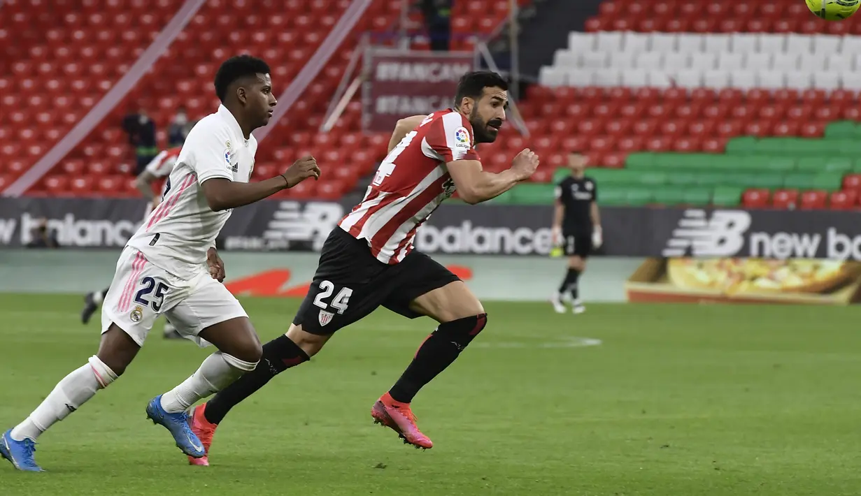 Penyerang Real Madrid, Rodrygo berebut bola dengan bek Athletic Bilbao, Mikel Balenziaga pada pekan ke-37 La Liga di San Mames, Minggu (15/5/2021). Real Madrid berhasil menang di laga sulit yang berlangsung di markas Bilbao dengan skor tipis 1-0. (AP Photo/Alvaro Barrientos)